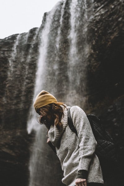 站在瀑布边的戴着针织帽的女人